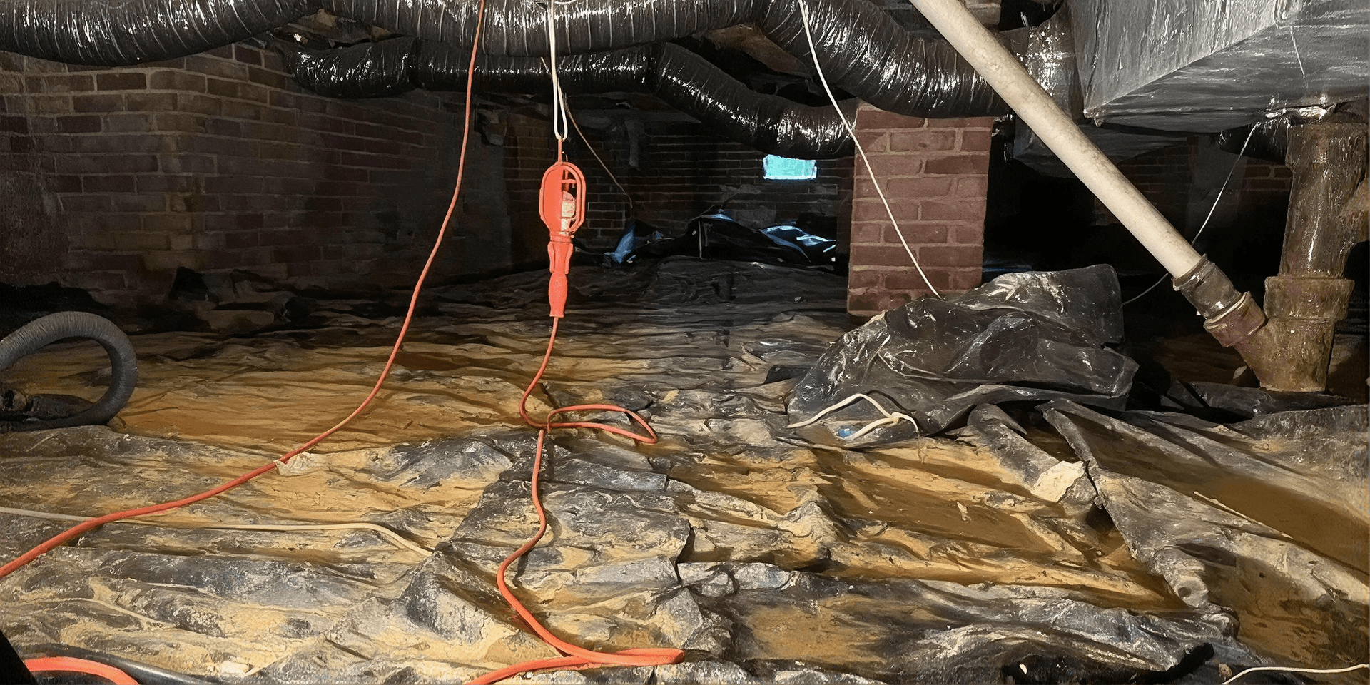 Crawlspace with a damaged and dirty vapor barrier, exposed brick supports, ductwork, plumbing, and electrical cords before encapsulation.