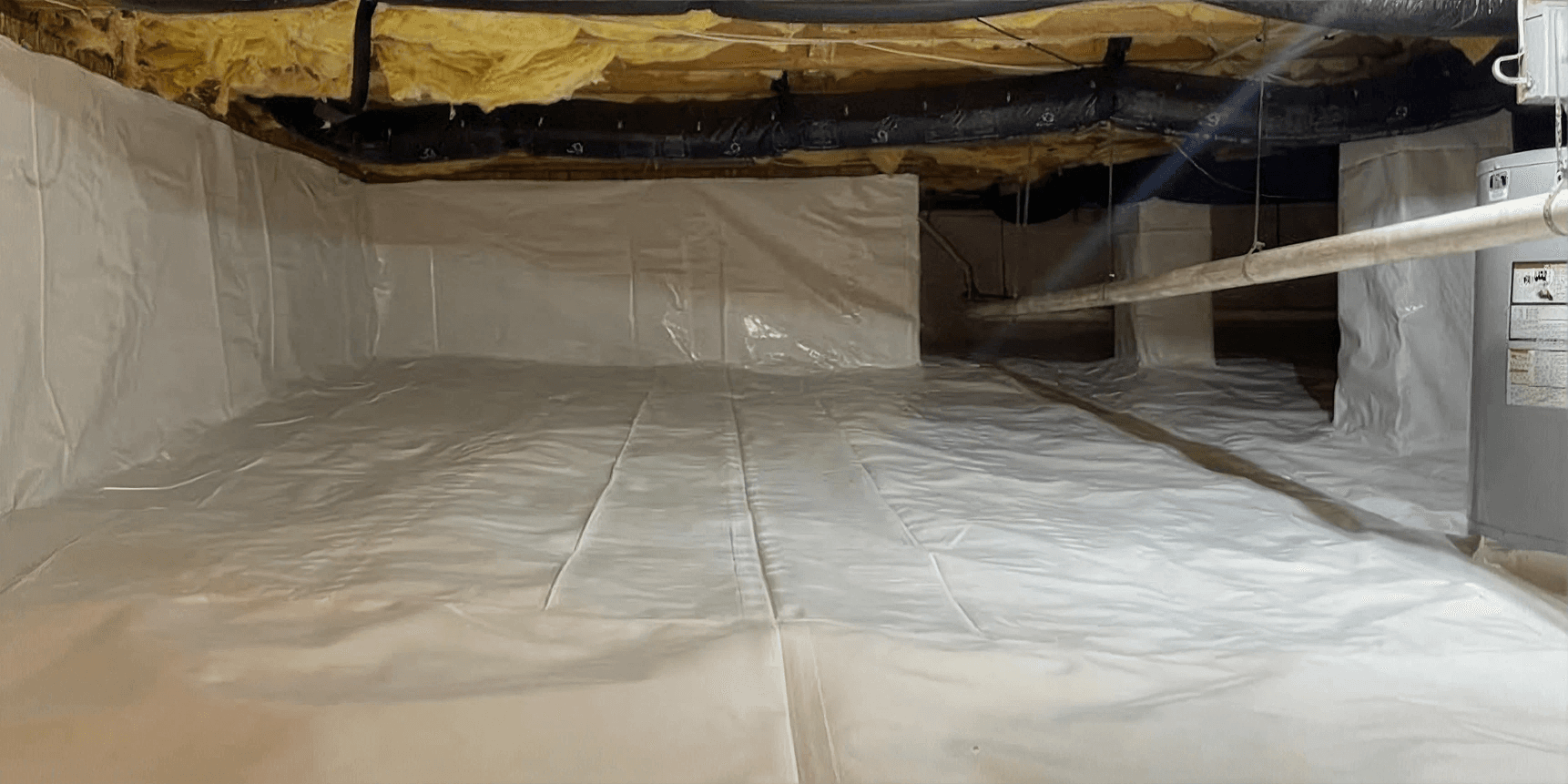 Professionally encapsulated crawlspace with a sealed white vapor barrier covering the floor and foundation walls to protect against moisture, improve energy efficiency, and support healthier indoor air quality.