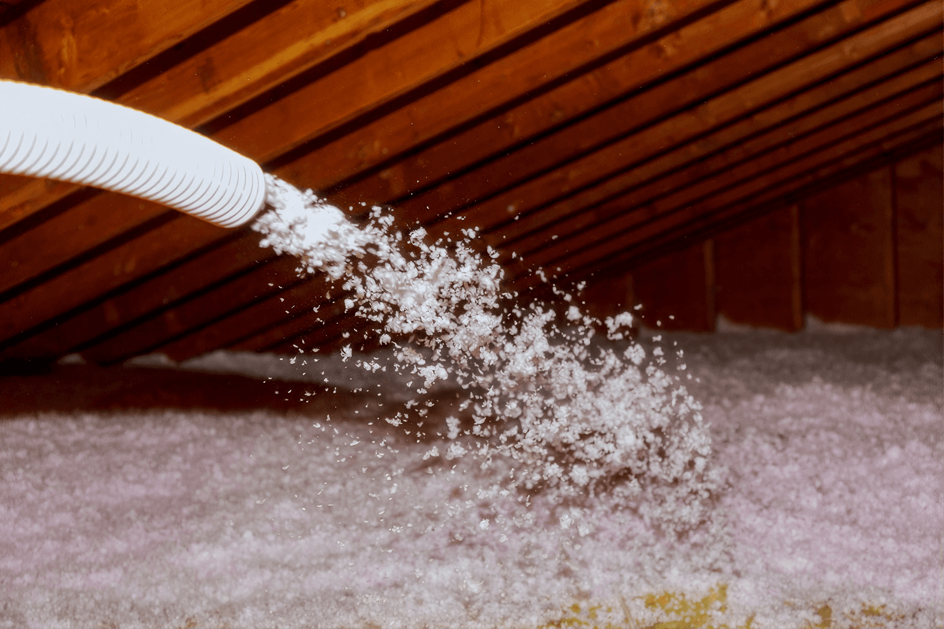 Blown-in insulation being installed in an attic using a flexible hose.