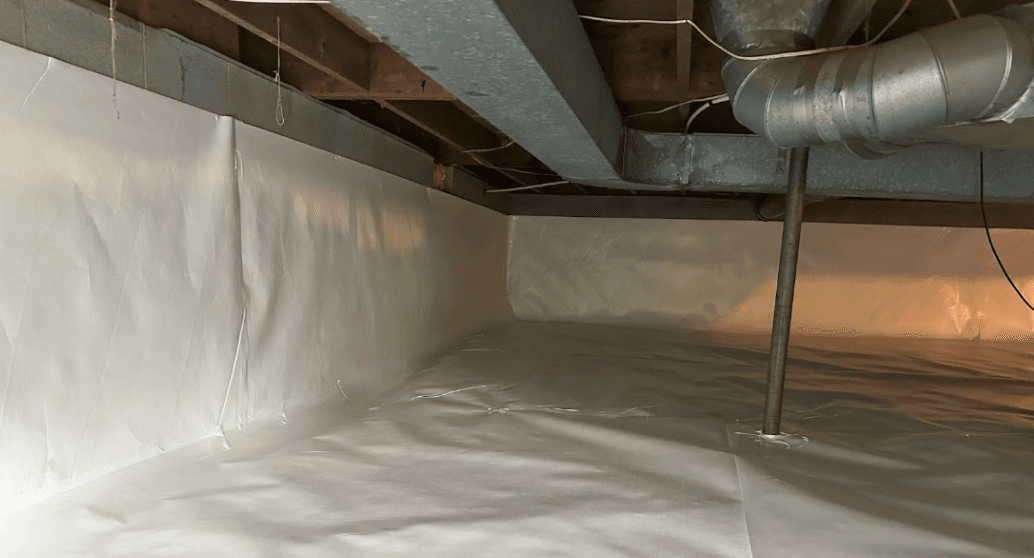 Low, unfinished crawlspace lined with white plastic vapor barrier, showing exposed wooden joists, metal HVAC ductwork, and support pipes.