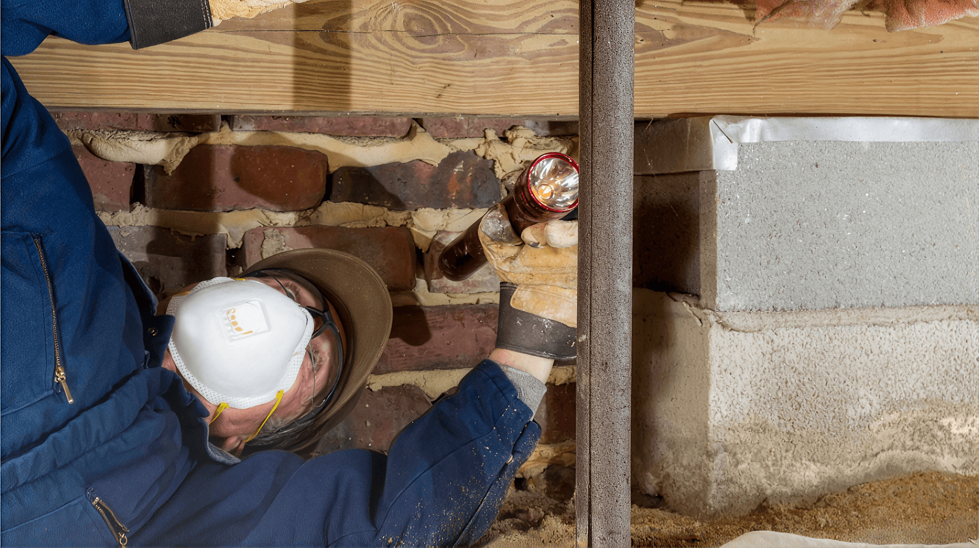Technician inspecting a crawl space foundation and support pier for signs of settlement, structural damage, or moisture issues as part of a professional foundation repair assessment.